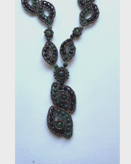 This pendant necklace features green gemstones woven into a stunning organic pattern - Sundara Joone.